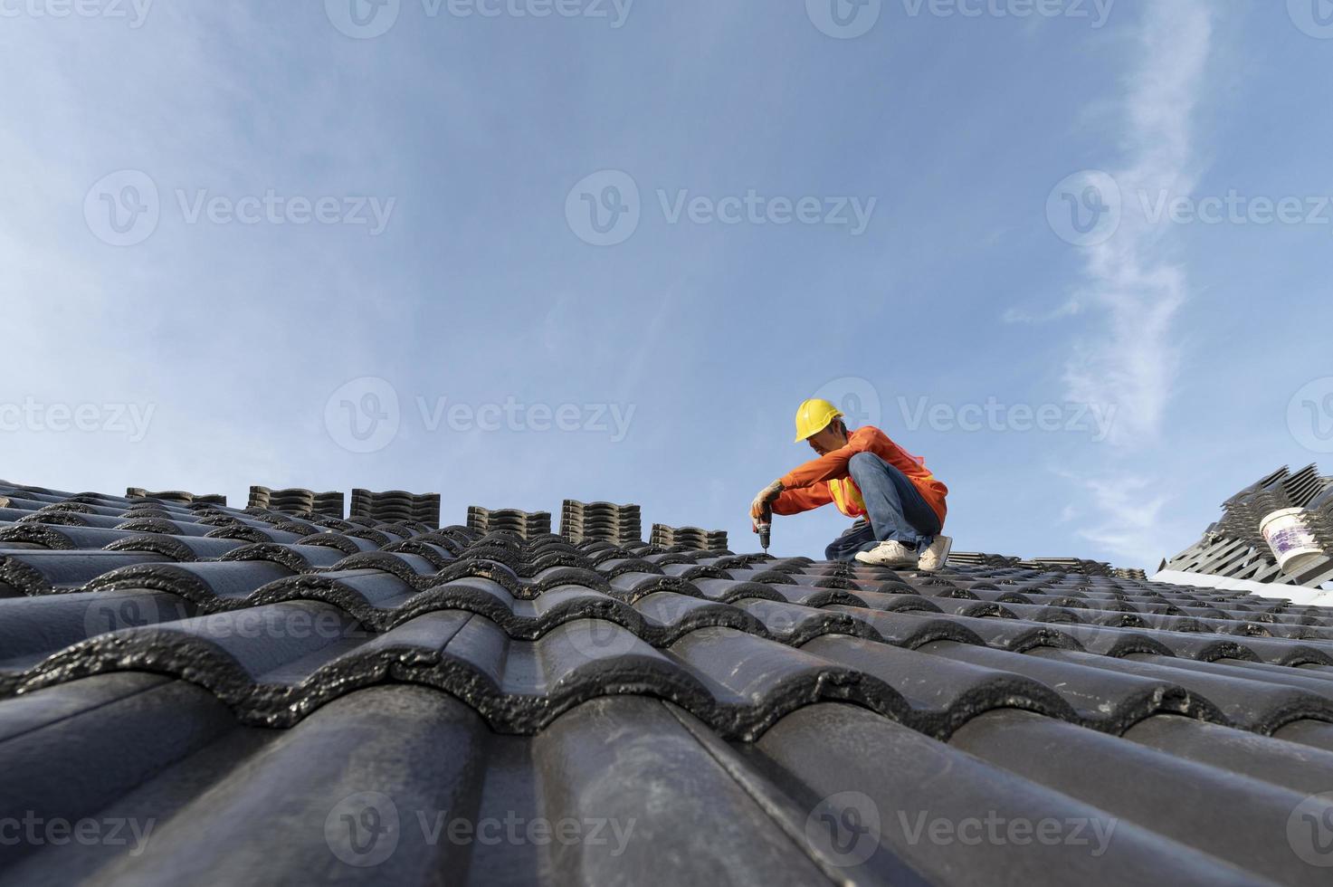 byggare i arbetskläder installerar nya takverktyg, takverktyg, elektrisk borr och använder dem på nya trätak med plåt foto