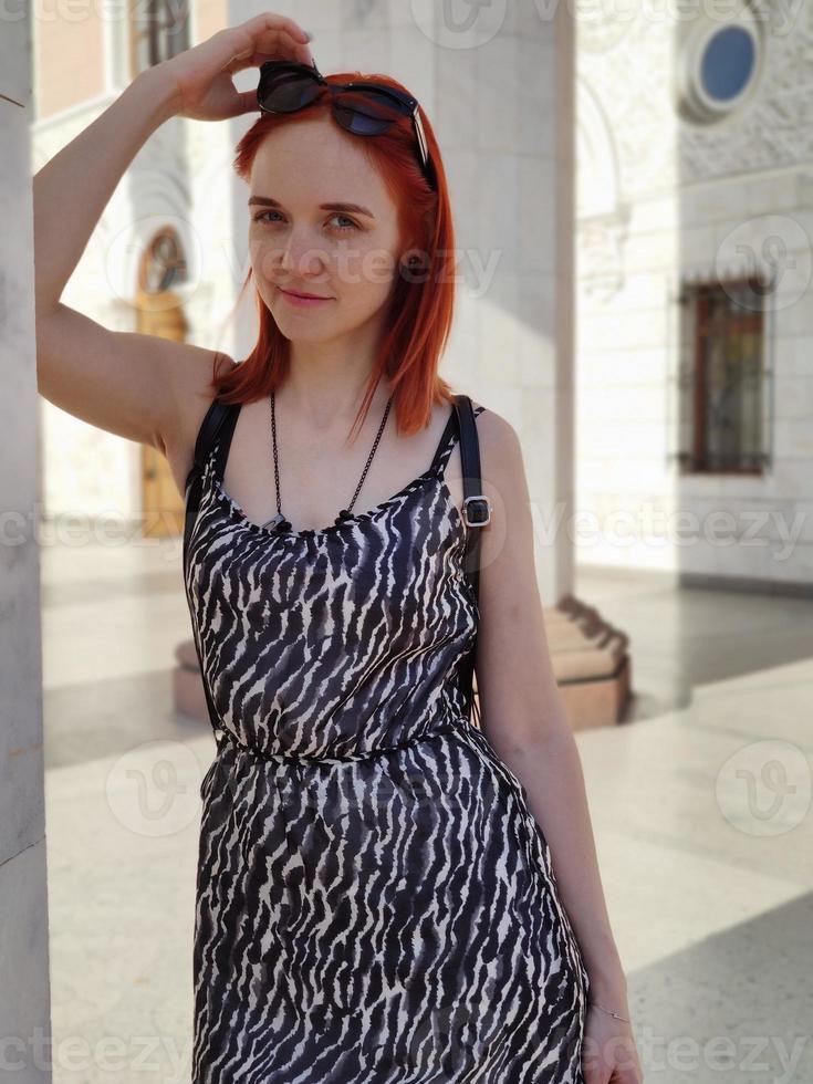 Söt ung europeisk rödhårig kvinna med en Lycklig leende i trevlig klänning foto