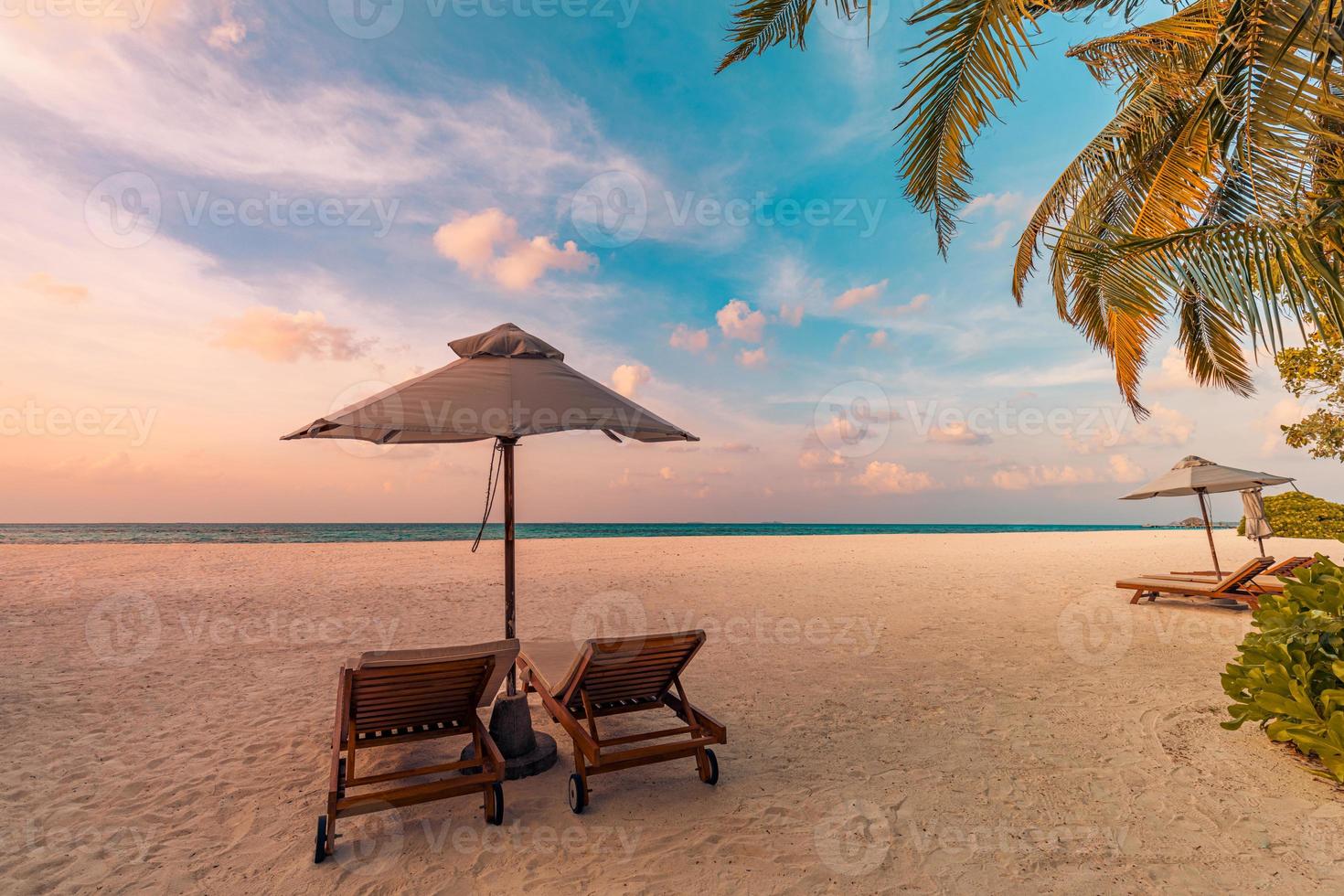 solnedgång strand. skön tropisk ö Strand, två Sol sängar solstol, parasoll under handflatan träd. sand hav horisont, färgrik dröm himmel, lugna koppla av. sommar semester strand landskap. romantisk par tillflykt foto