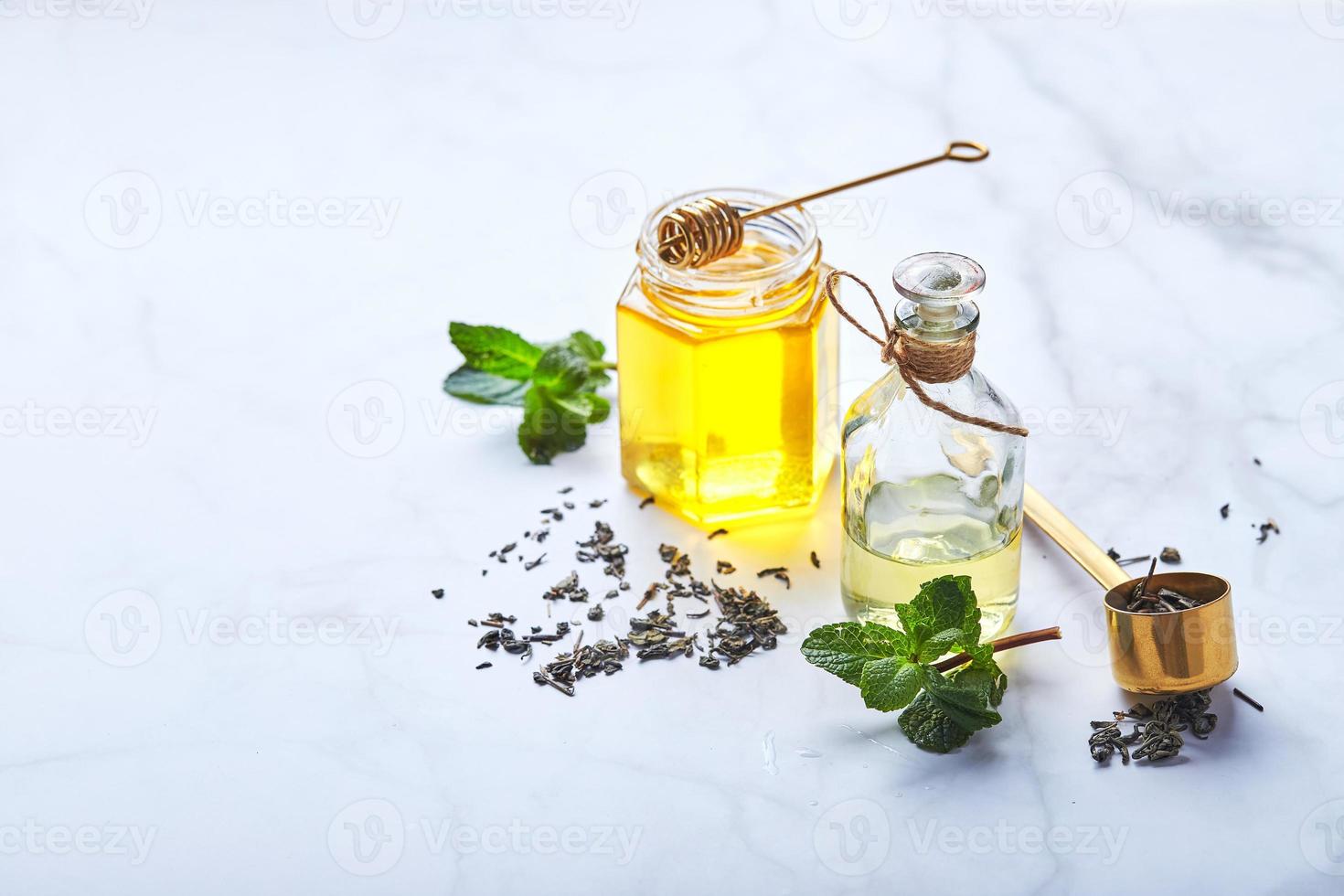 flaska av grundläggande olja av mynta och grön löv och burk av honung. naturlig organisk Ingredienser för kosmetika, hud vård, kropp vård. skönhet vård begrepp foto