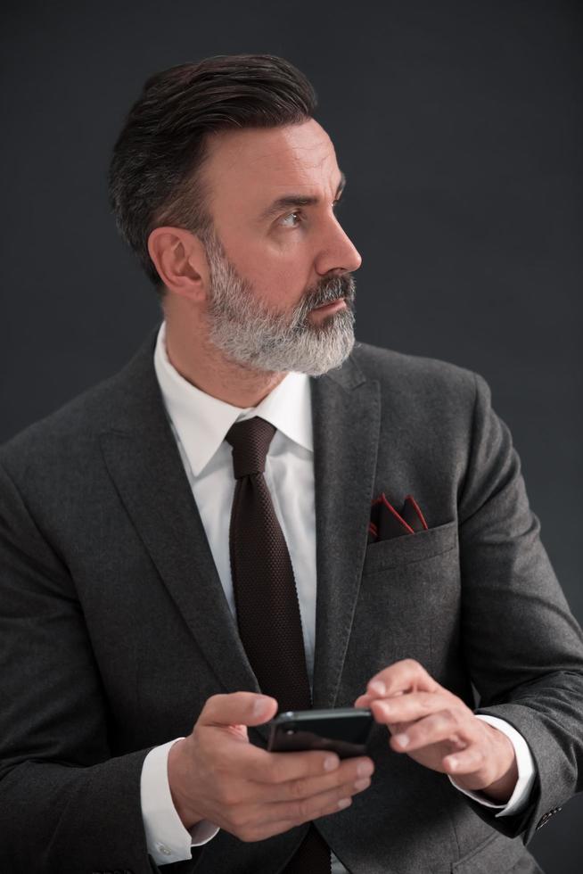 porträtt av vuxen affärsman bär trendig kostym och Sammanträde i modern studio på eleganta stol mot de svart bakgrund foto
