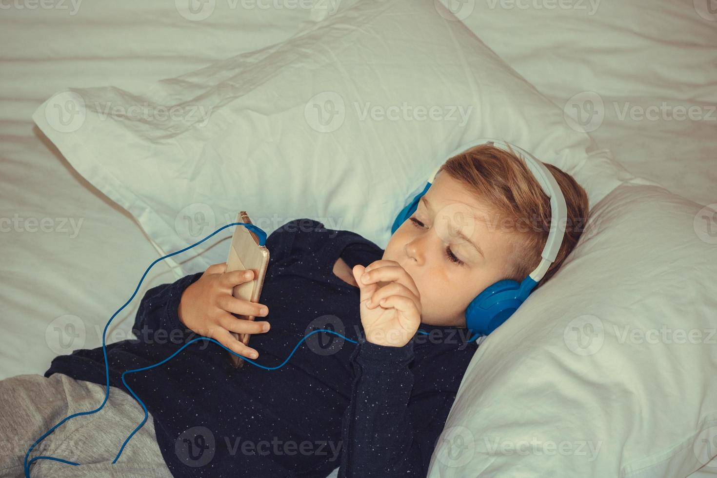 pojke med hörlurar tittar på tecknade serier på smart telefon. foto