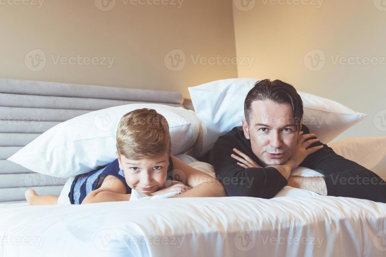far och son avkopplande på de säng på Hem. foto