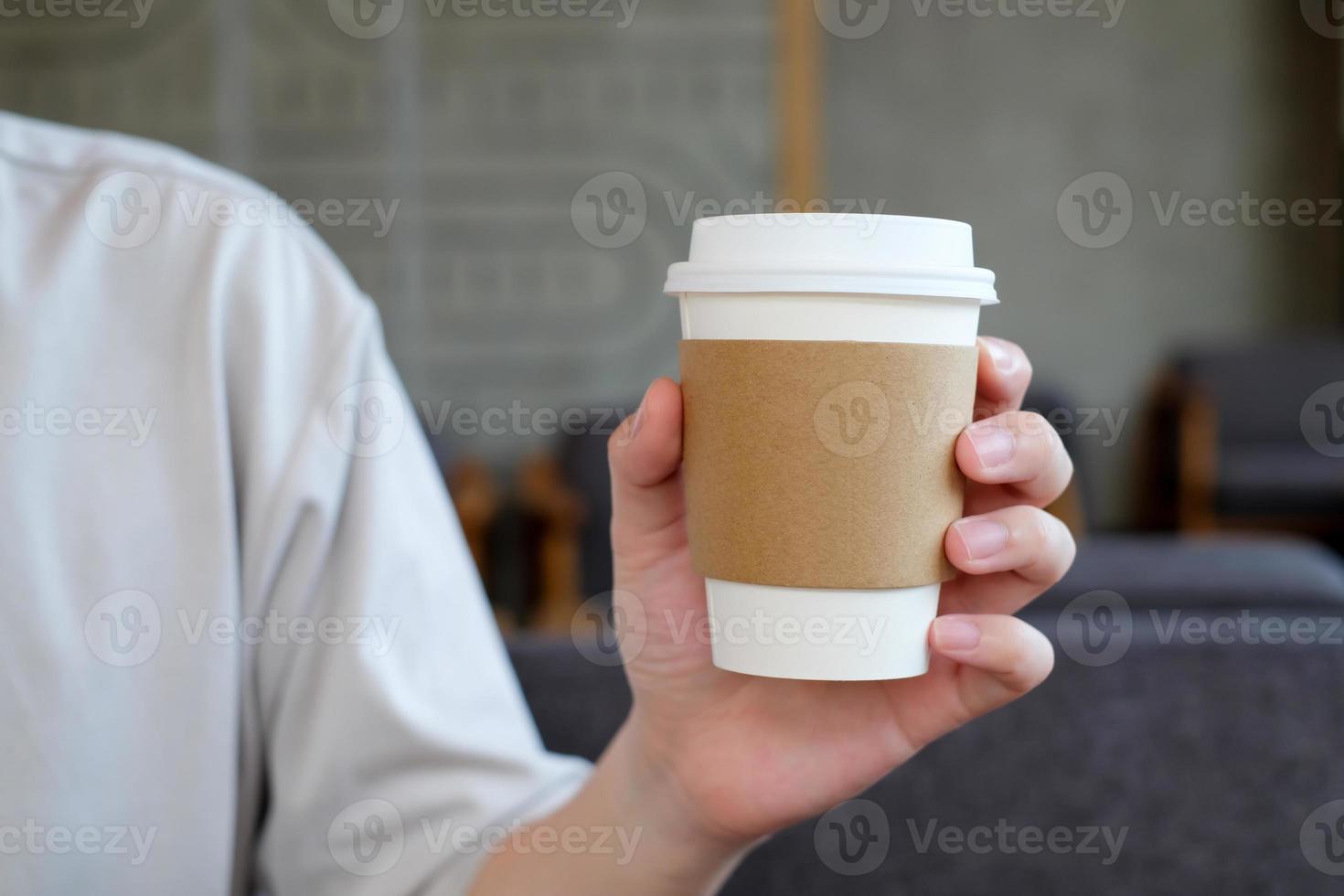 man hand innehav brun papper kopp av varm dryck i kaffe Kafé. ta bort varm dryck kopp. foto