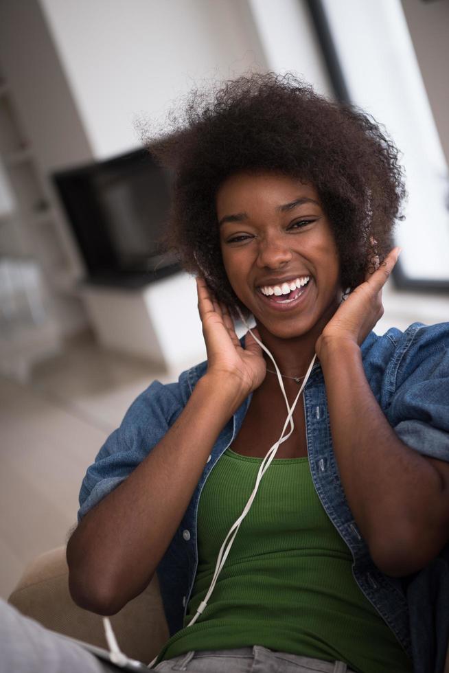 afrikansk amerikan kvinna på Hem i stol med läsplatta och huvud telefoner foto