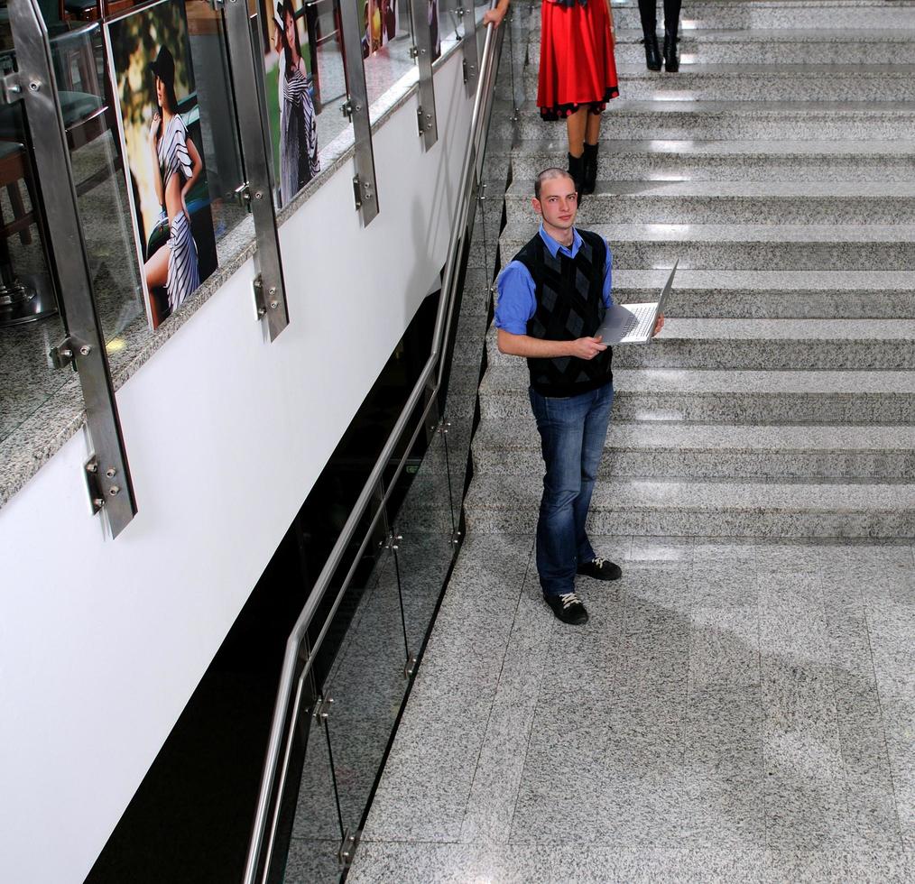 ung företag man stående på trappa och håll bärbar dator foto
