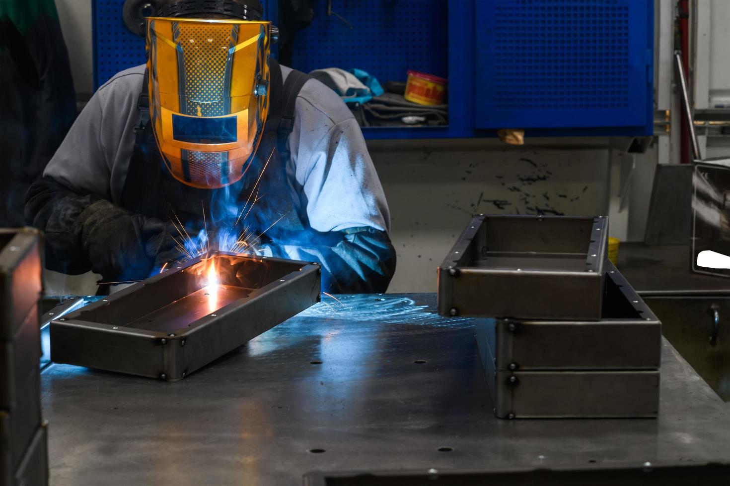 professionell svetsare utför arbete med metall delar i fabrik, gnistor och elektricitet. industri arbetstagare baner. foto