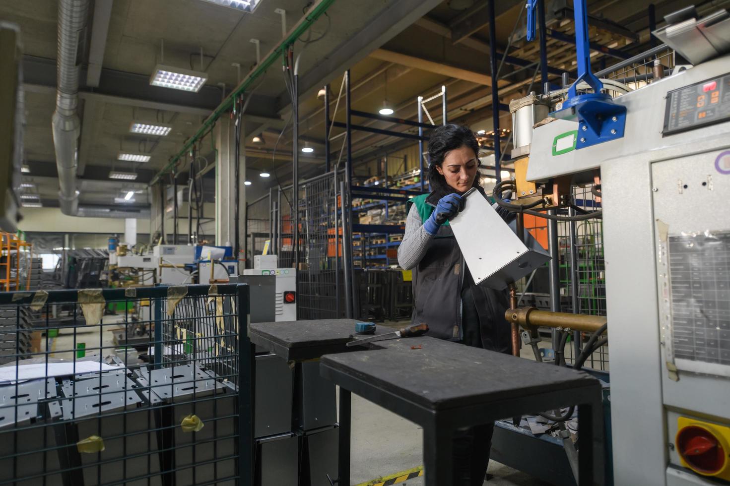 Kalkon, 2022 - en kvinna arbetssätt i en modern metall fabrik sätter ihop delar för en ny maskin foto