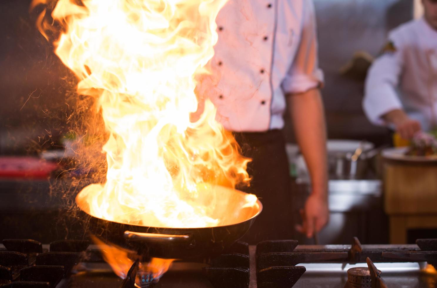 kock håller på med flambe på mat foto