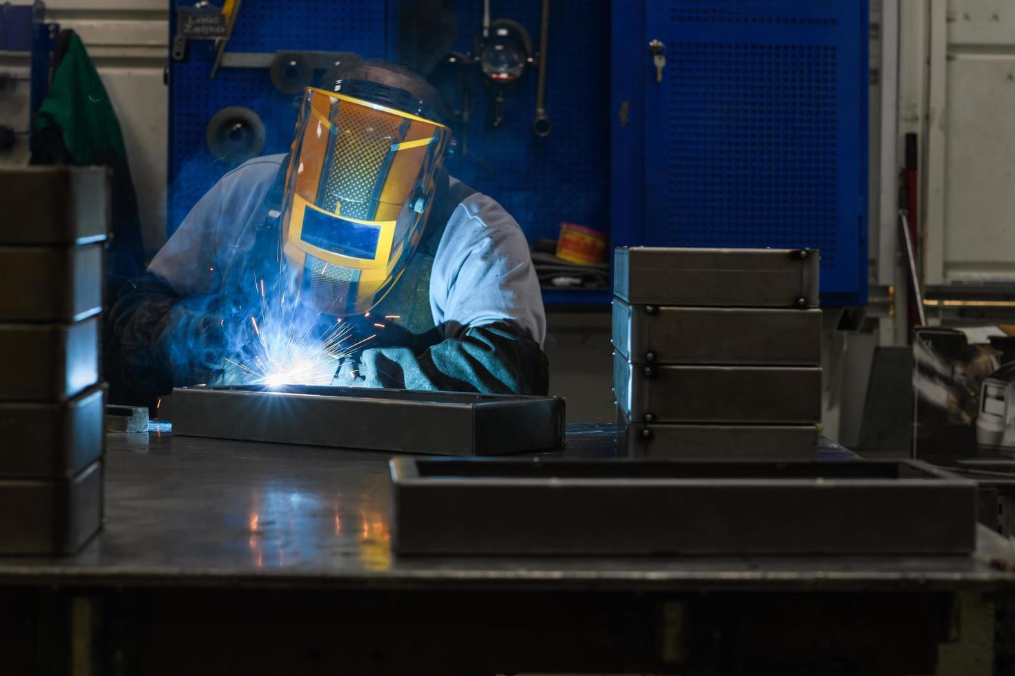 professionell svetsare utför arbete med metall delar i fabrik, gnistor och elektricitet. industri arbetstagare baner. foto