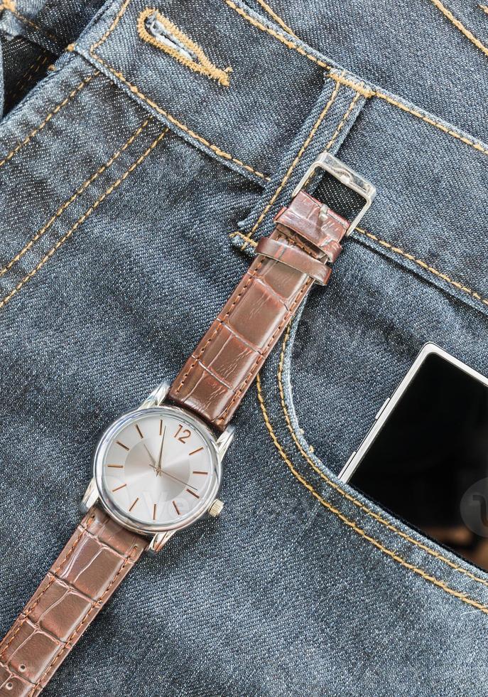 armbandsur och smartphone på jeans foto