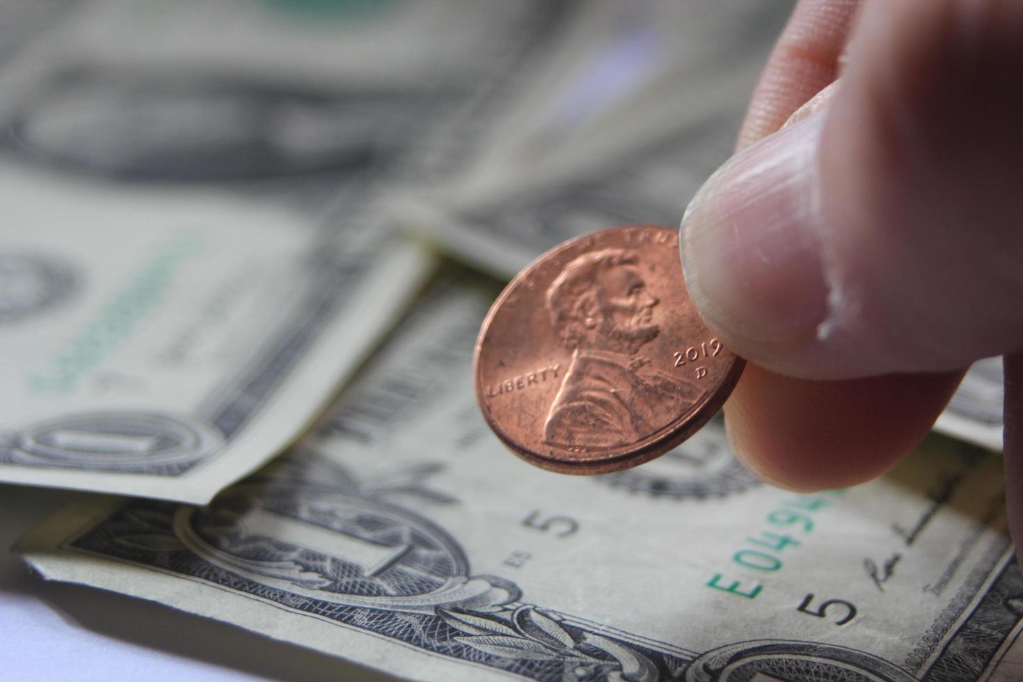 mannens hand plockning upp penny eller cent mynt från en lugg av sedlar och mynt. foto