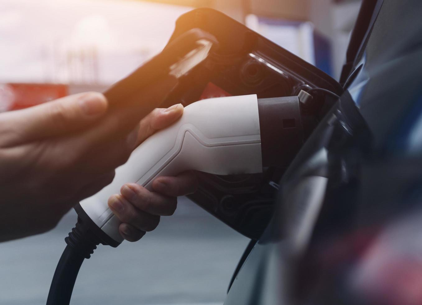 hand plugging i en laddare i ett elektrisk bil socket.electric bil eller ev är laddning på station foto