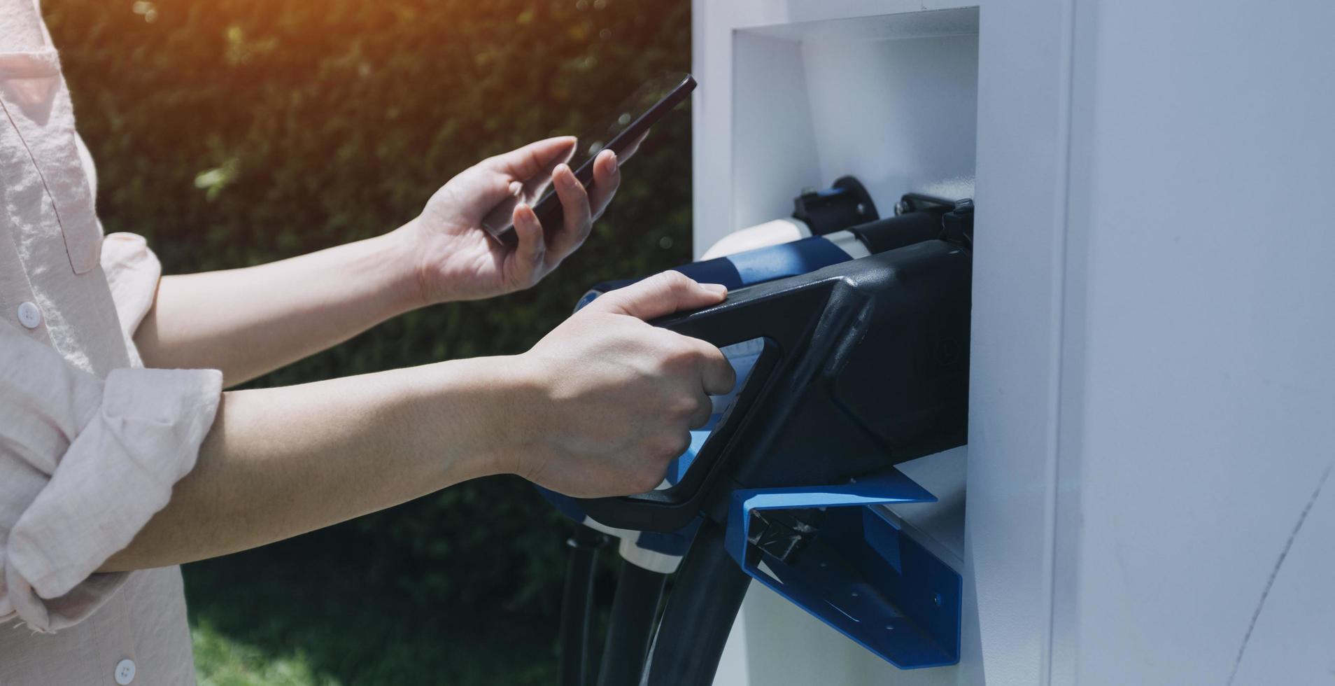 hand plugging i en laddare i ett elektrisk bil socket.electric bil eller ev är laddning på station foto