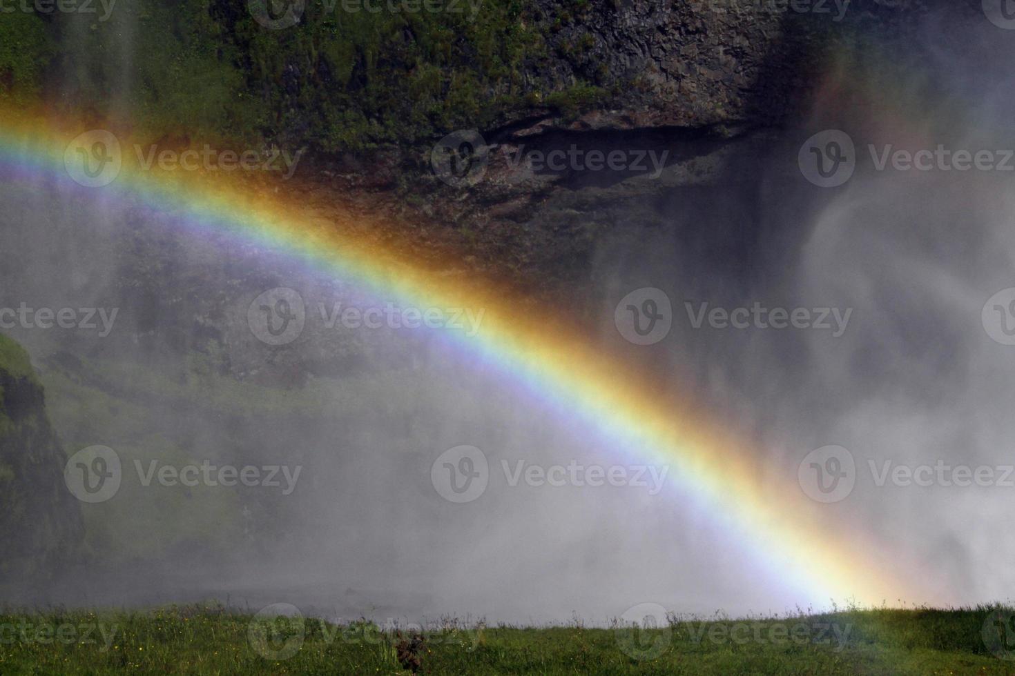 en regnbåge i främre av Seljalandsfoss vattenfall på de sydlig kust av island på en solig dag foto