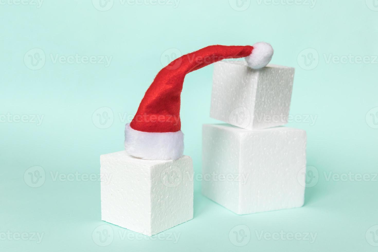 helt enkelt minimal sammansättning vinter objekt tomte hatt och kub former geometrisk form podium isolerade blå pastell bakgrund. jul nyår december tid för firande koncept. mockup, kopiera utrymme foto