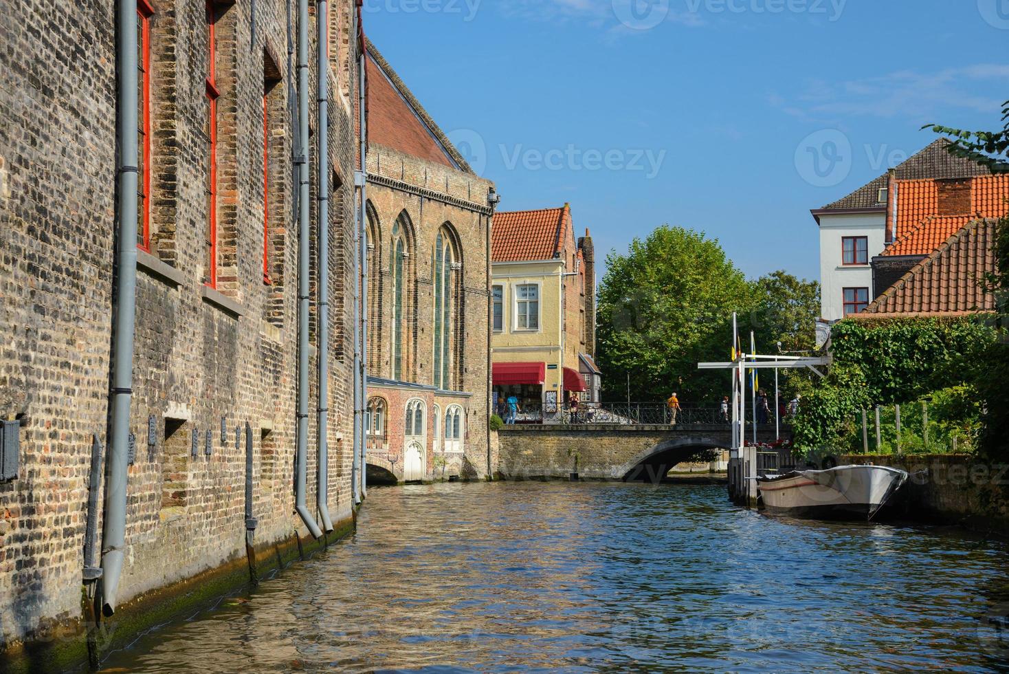 se från de kanal till de bro, båt och gammal tegel handlare hus i Brugge, Belgien. gammal medeltida Europa stad se. foto