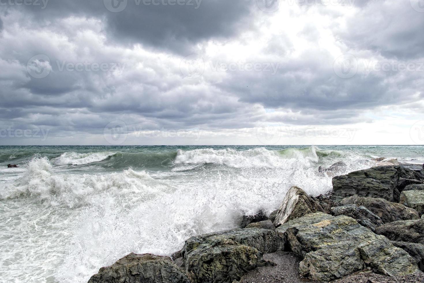 hav i storm på stenar av italiensk by foto