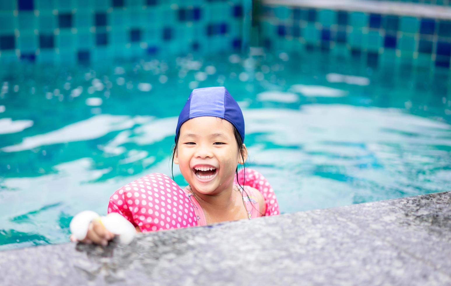 ung asiatisk flicka som leker i en pool foto