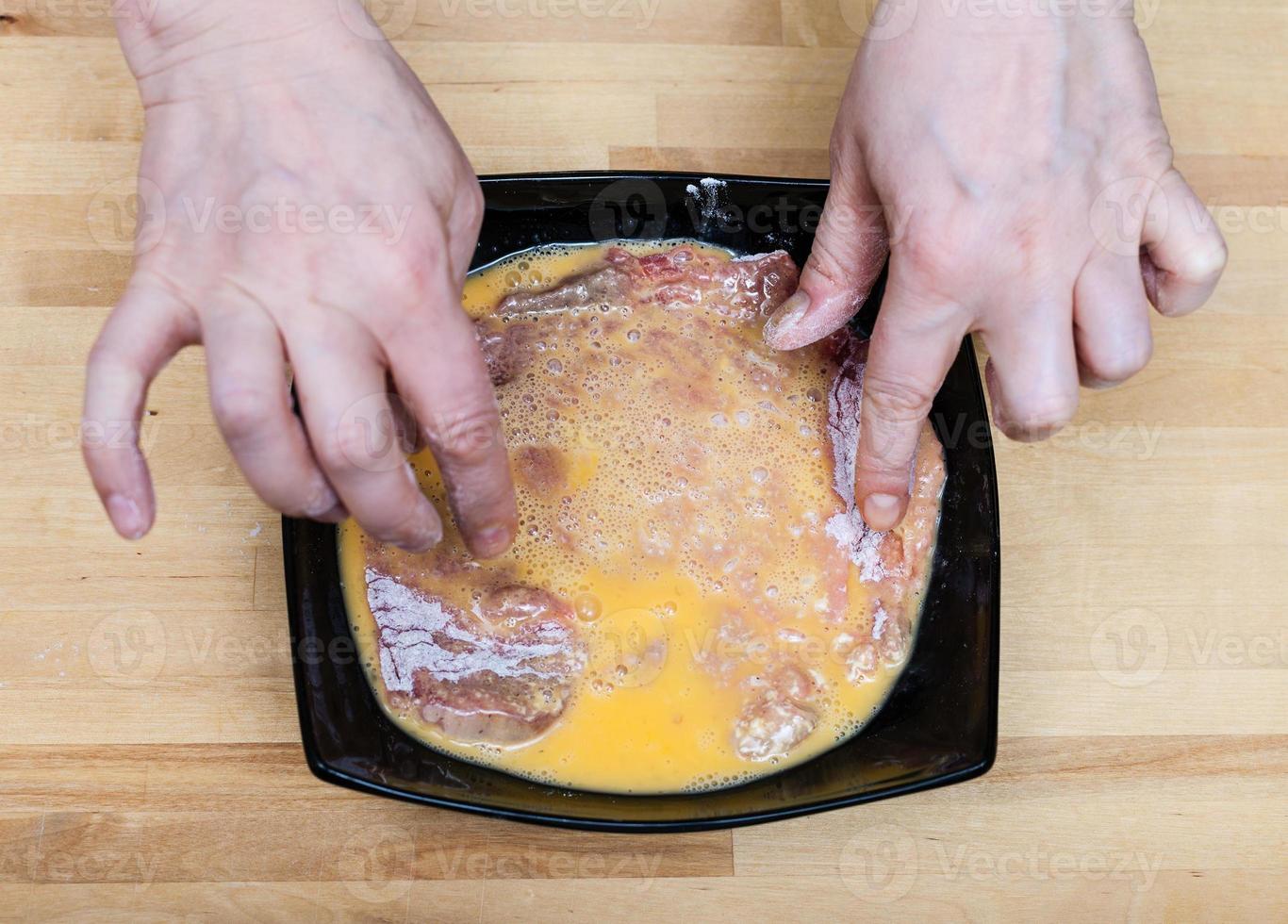 laga mat händer bröd en rå kalvkött schnitzel i ägg foto