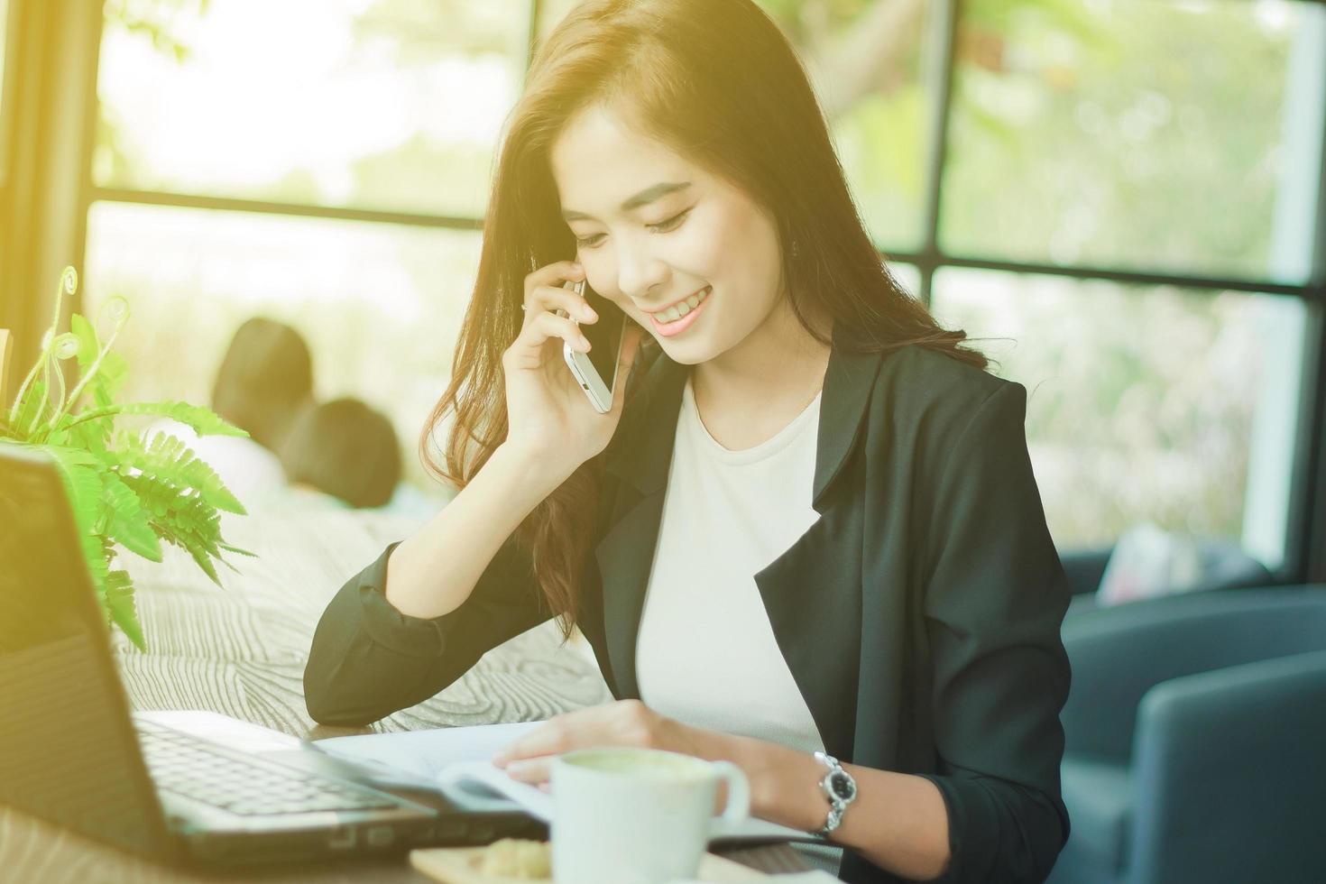 ung asiatisk professionell kvinna använder sin mobiltelefon på jobbet foto