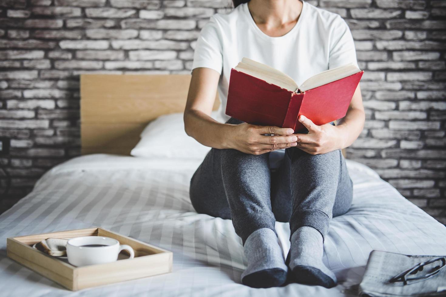 ung kvinna njuter av en bok i sängen foto