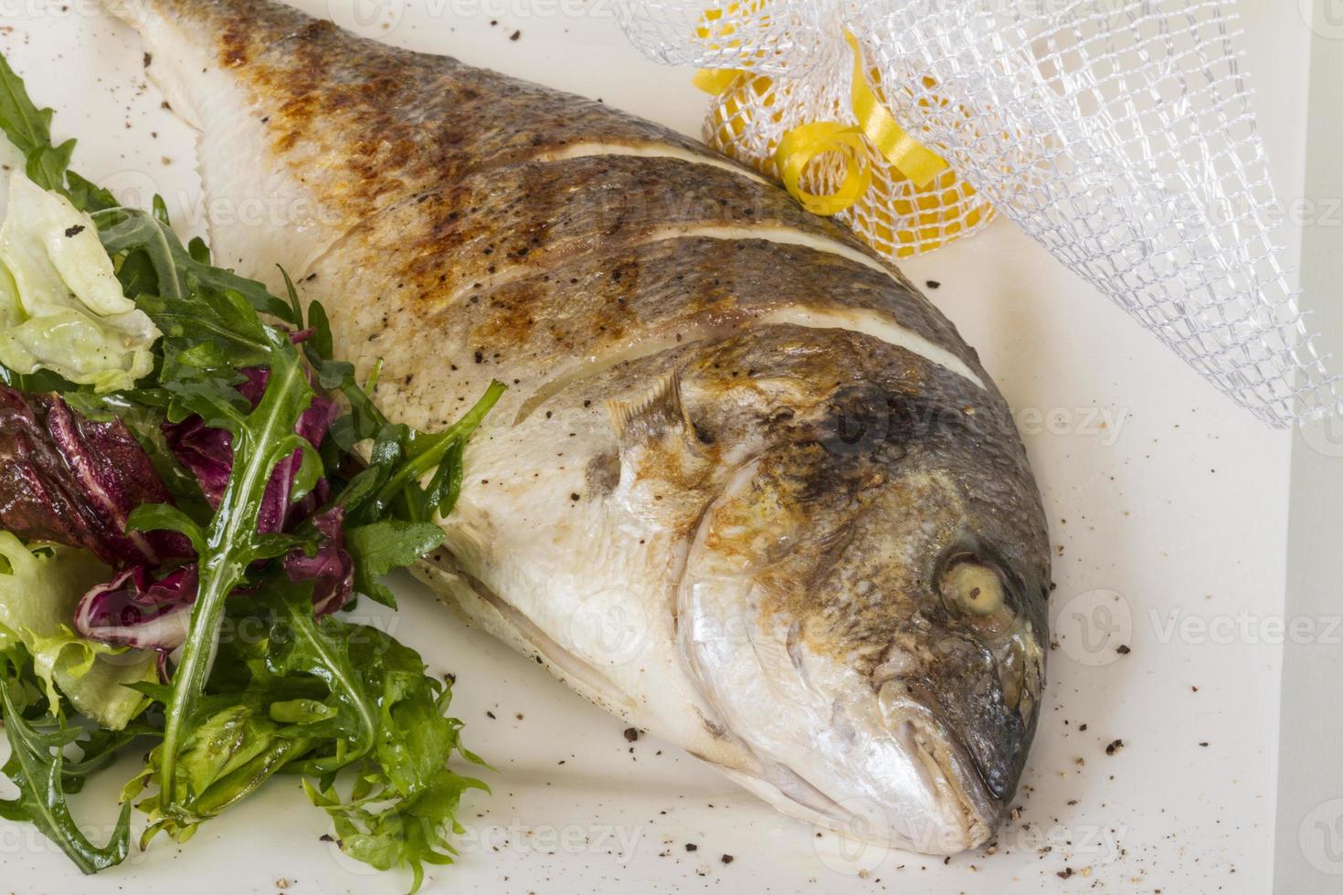 dorada fisk med sallad på den vita plattan. studio skott foto