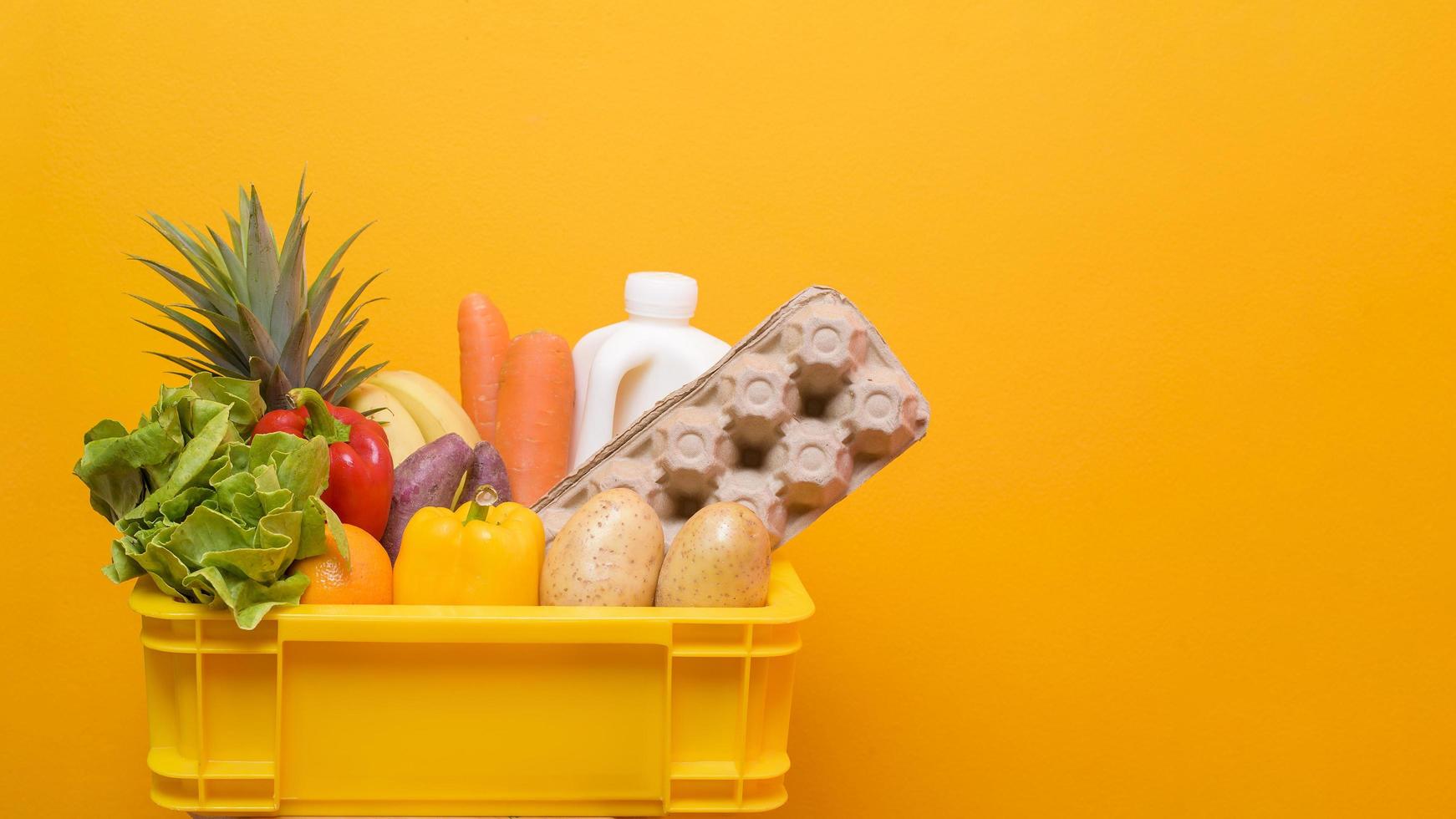 låda med matvaror på gul bakgrund foto