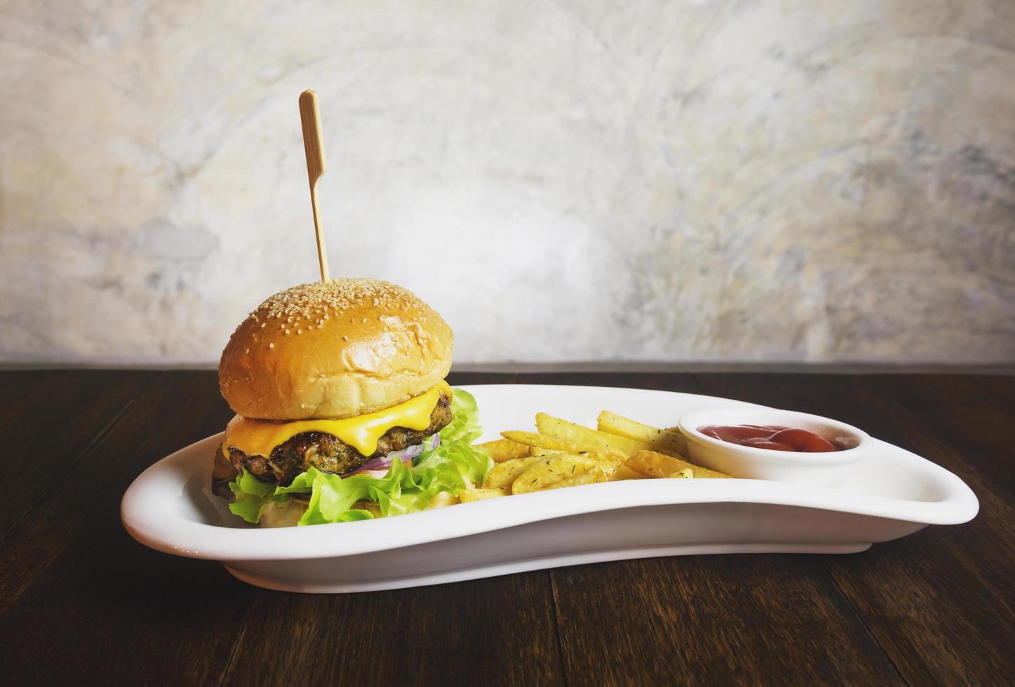 cheeseburger och pommes frites på den vita plattan foto