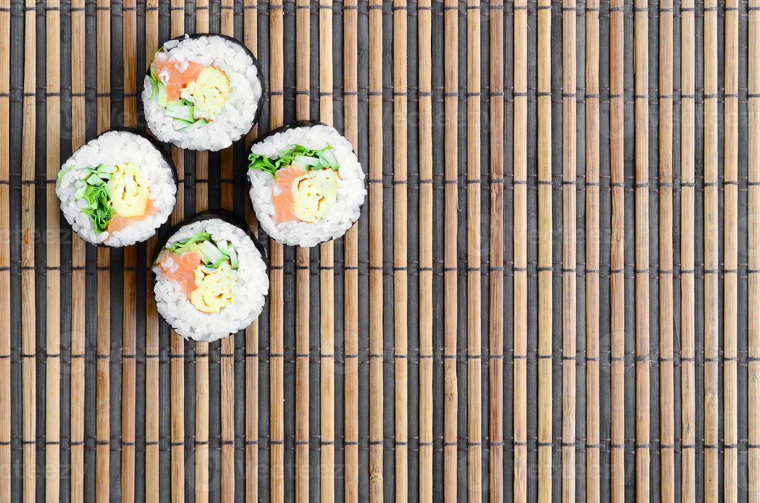 sushi rullar lögner på en bambu sugrör serving matta. traditionell asiatisk mat. topp se. platt lägga minimalism skott med kopia Plats foto