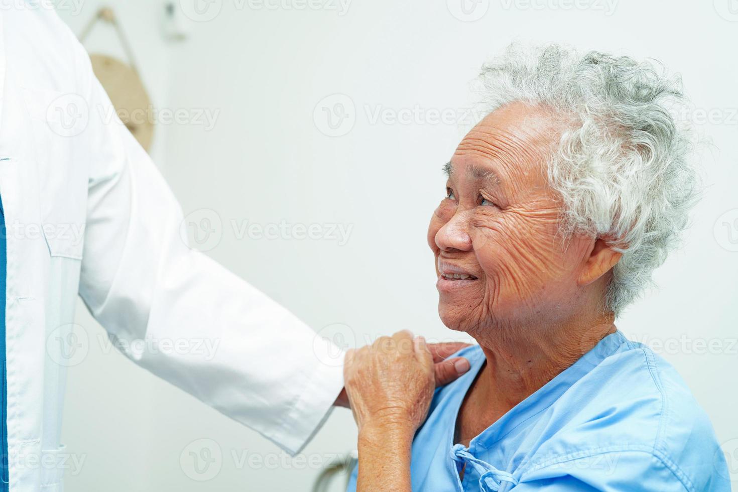 läkare som tar hand om, hjälper och uppmuntrar asiatisk äldre äldre kvinna patient på kliniken sjukhus. foto