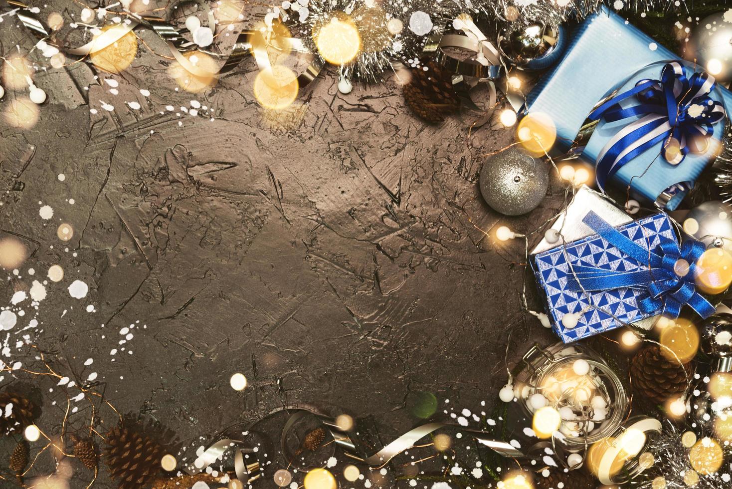 julklapp med blått band och juldekoration bollar på abstrakt bokeh svart bakgrund med kopia utrymme. semester bakgrund gratulationskort för god jul och nytt år. foto