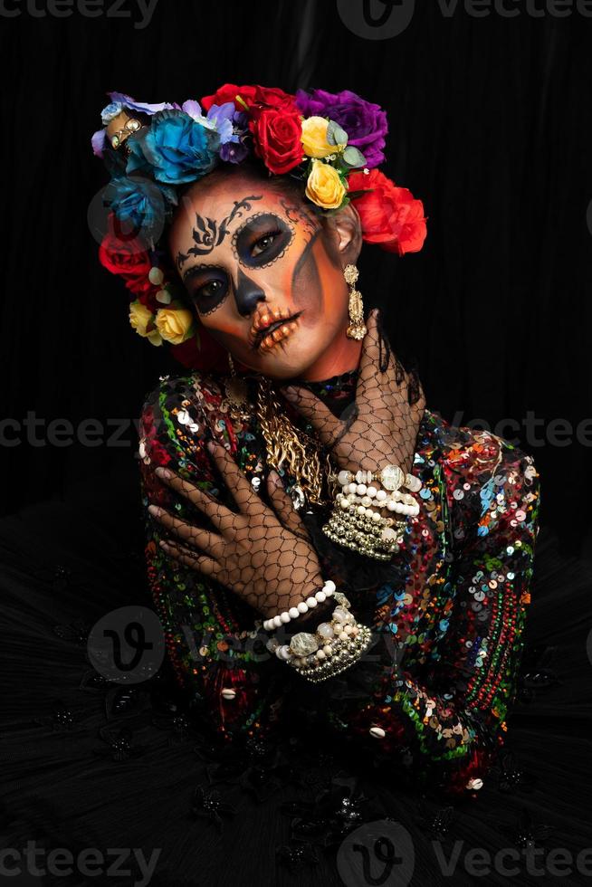 närbild porträtt av en kvinna med en socker skalle smink klädd med blomma krona. halloween begrepp foto