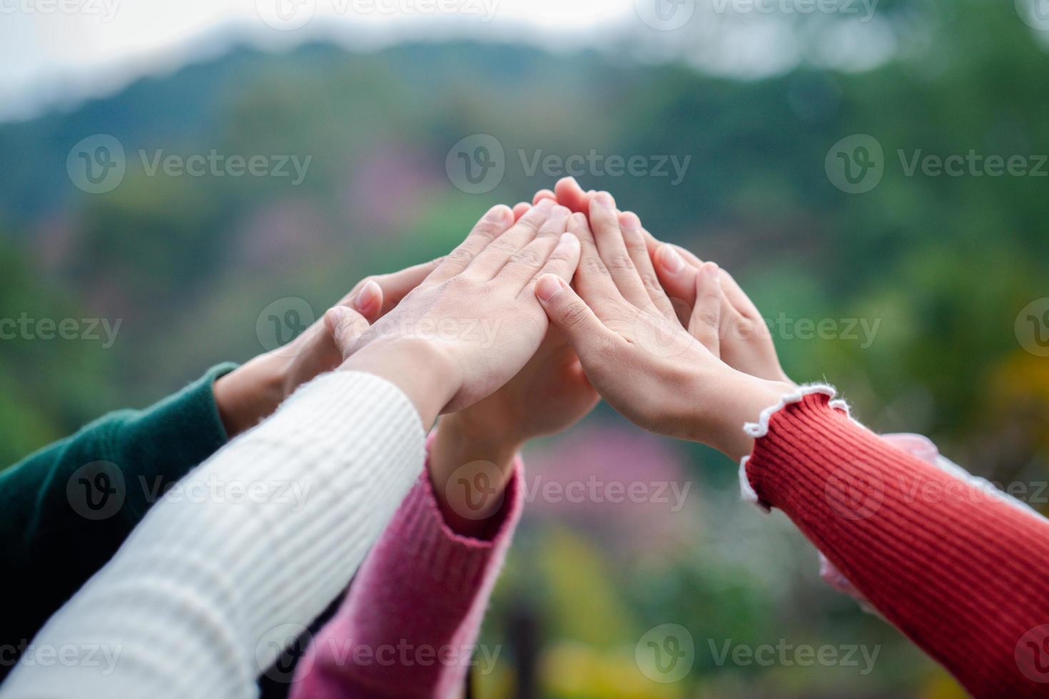 en mångfaldig grupp människor förbinder sina händer som ett stödjande tecken som uttrycker en känsla av lagarbete. enhet och samhörighet. foto