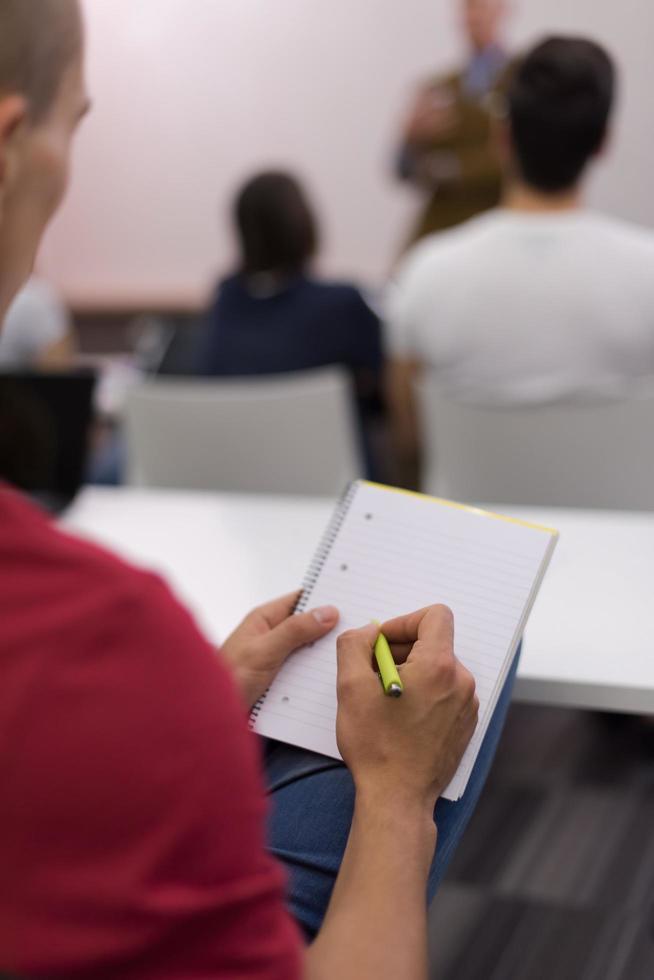 manlig studerande tar anteckningar i klassrum foto