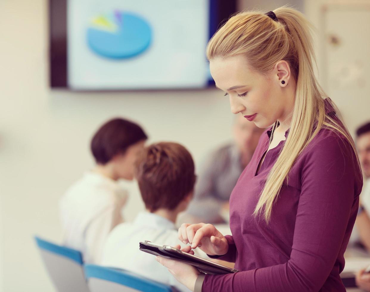 blond affärskvinna arbetssätt på läsplatta på kontor foto