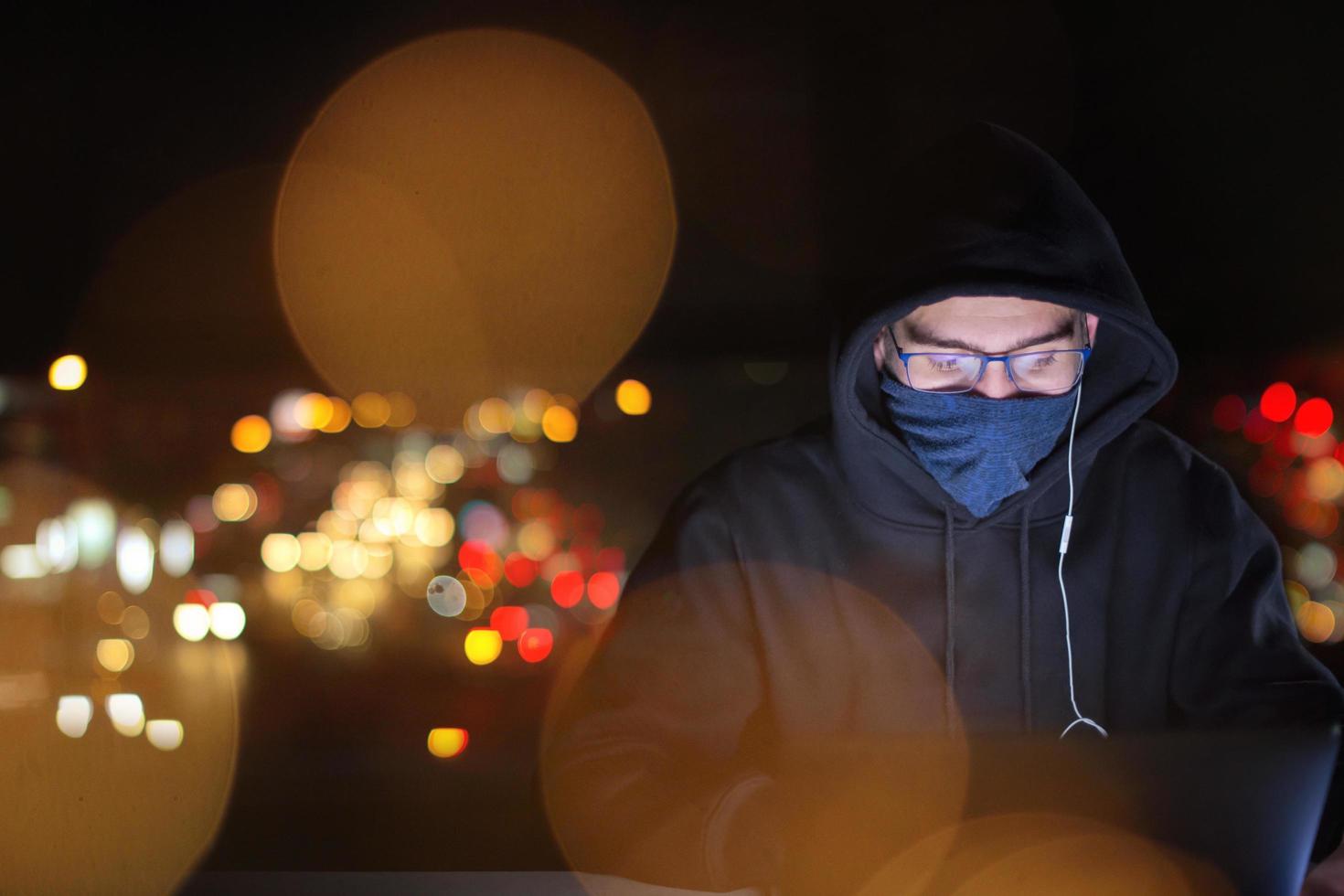 hacker använder sig av bärbar dator dator medan arbetssätt i mörk kontor foto