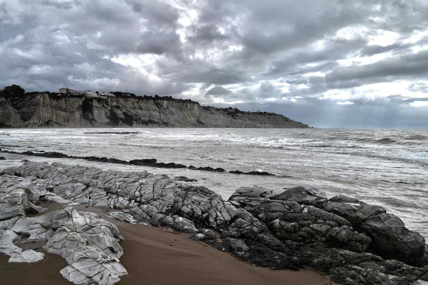 grå stenar nära havet under grå himmel foto