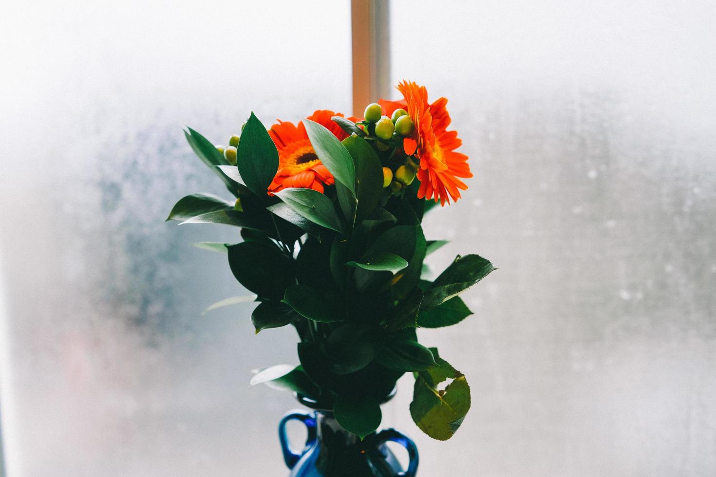 orange blommor i blå vas foto