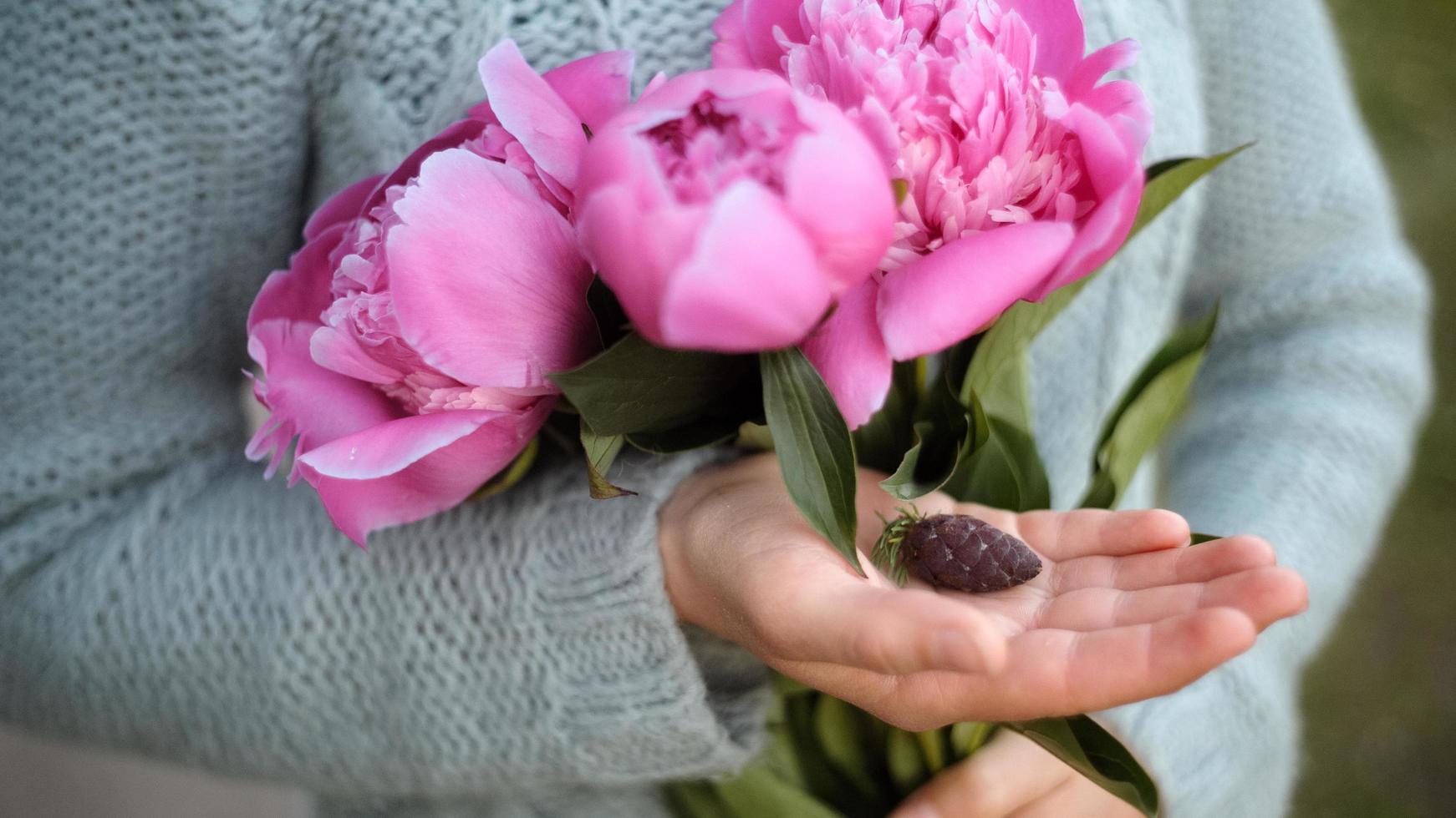 kvinna som håller pioner och pinecone foto