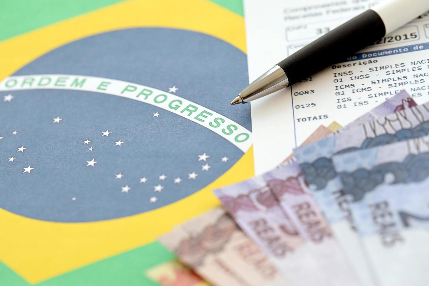 ternopil, ukraina - Maj 20, 2022 brasiliansk bevis av samling Rapportera med brasiliansk reals pengar räkningar och penna på nationell flagga bakgrund. brasiliansk Rättslig skattebetalande och beskatta rapportering foto