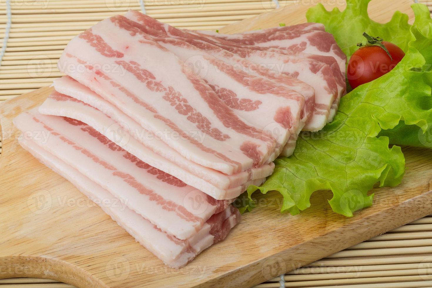skivad bacon på trä- styrelse och trä- bakgrund foto
