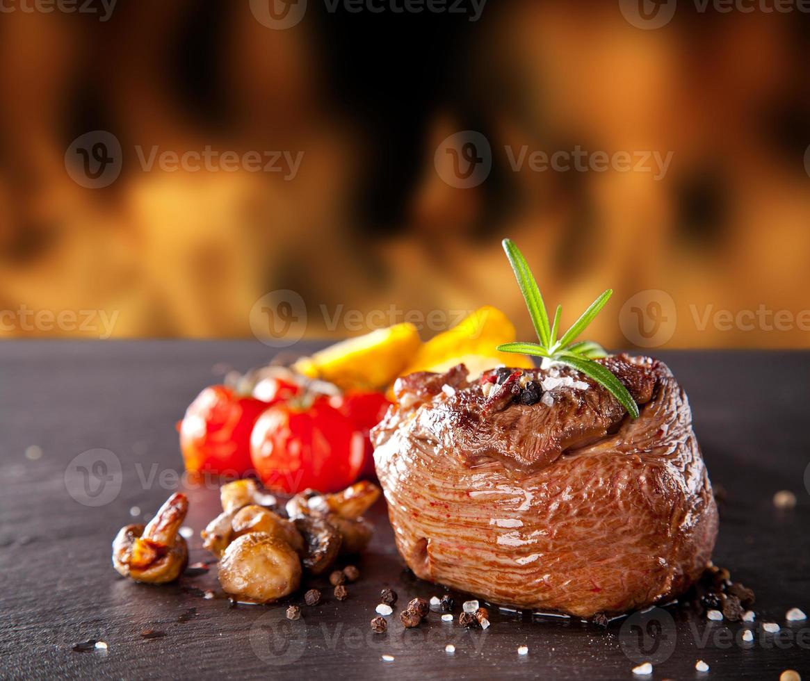 färsk nötköttbiff på svart sten och eld foto
