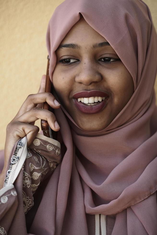 afrikansk kvinna använder sig av smartphone bär traditionell islamic kläder foto