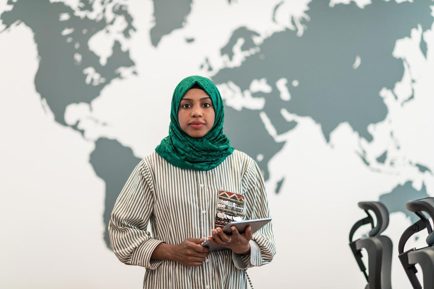 porträtt av muslim kvinna programvara utvecklare med grön hijab innehav läsplatta dator medan stående på modern öppen planen börja kontor foto
