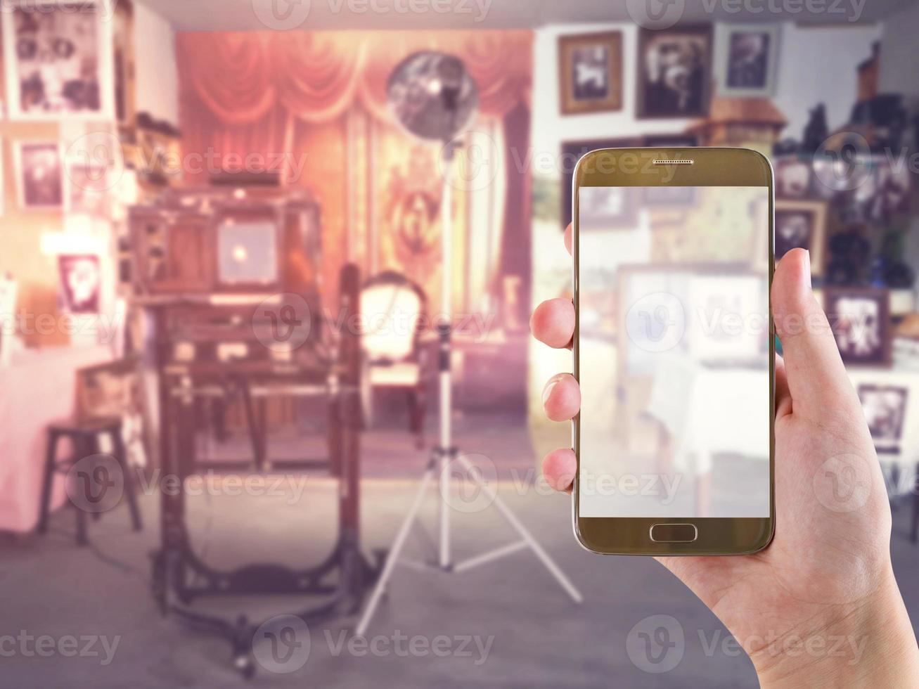 hand innehav mobil smart telefon med årgång studio rum fläck bakgrund foto