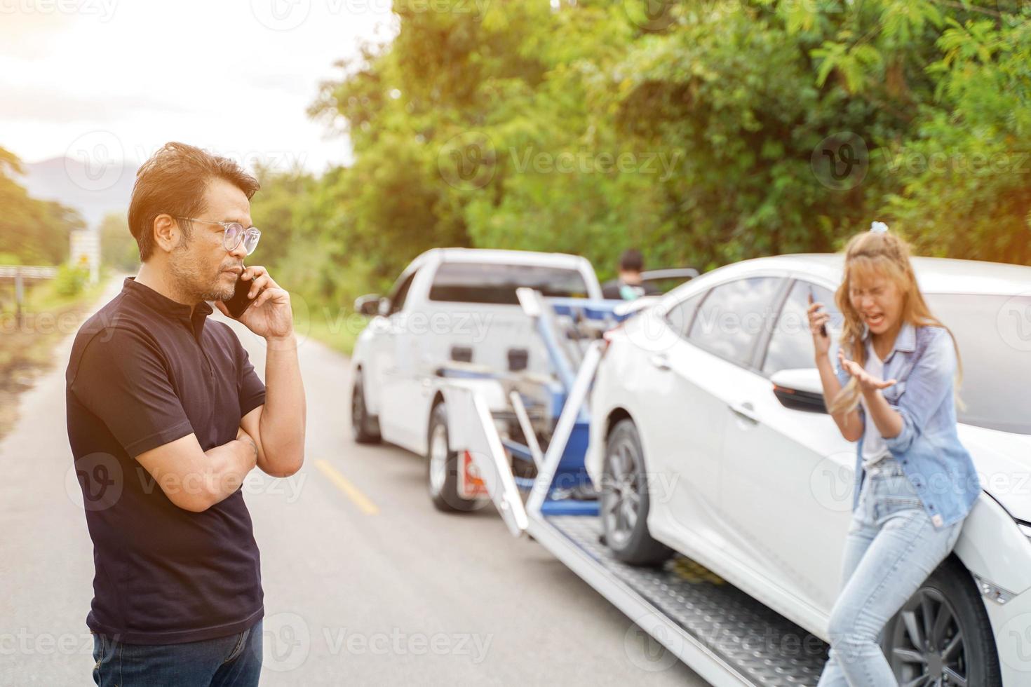 närbild förare i bil olycka använder sig av mobil telefon med skadad bil lastbil diabilder på landsbygden och Sol blossa bakgrund. foto