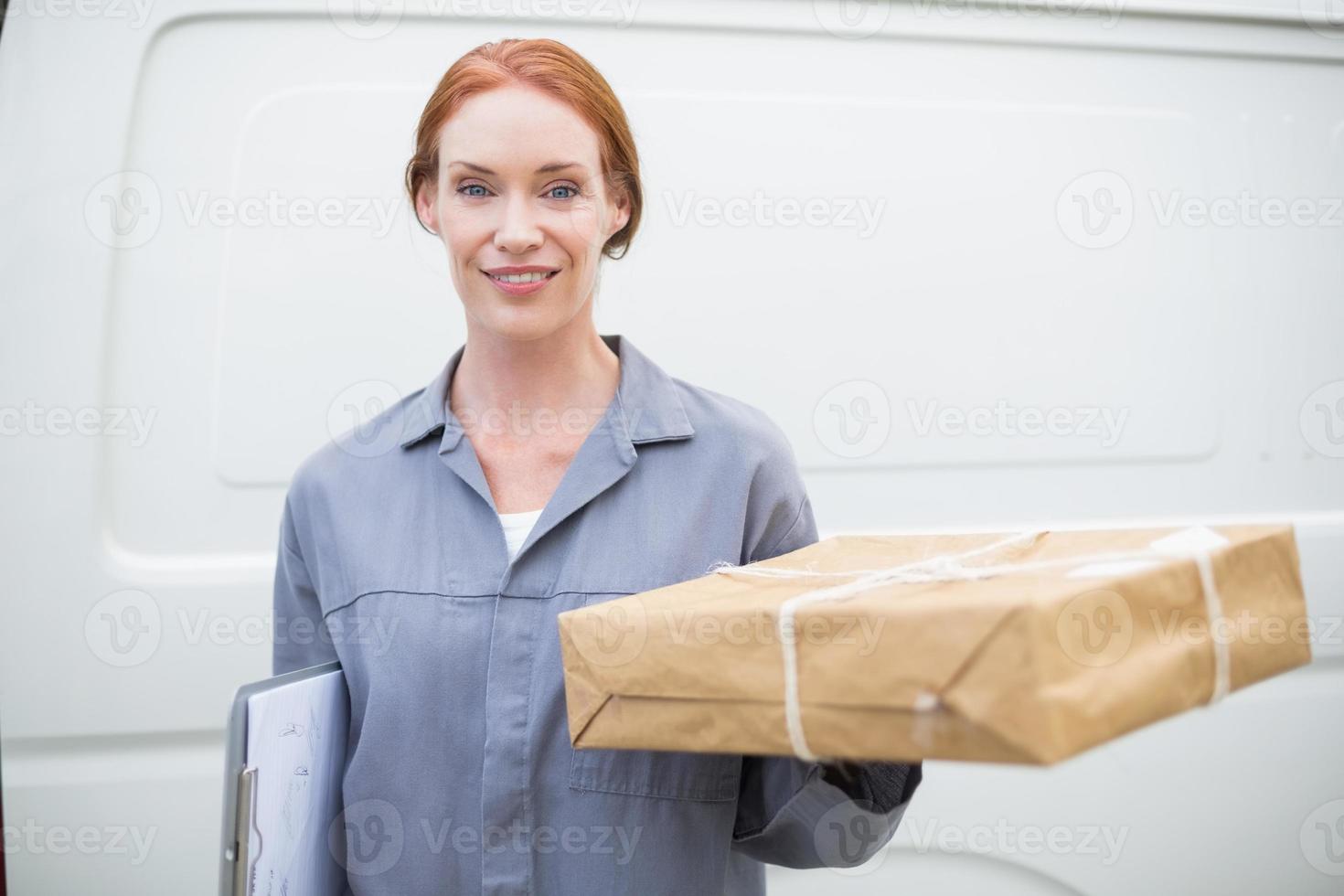 leveransförare som ler mot kameran av hennes skåpbil som håller paketet foto