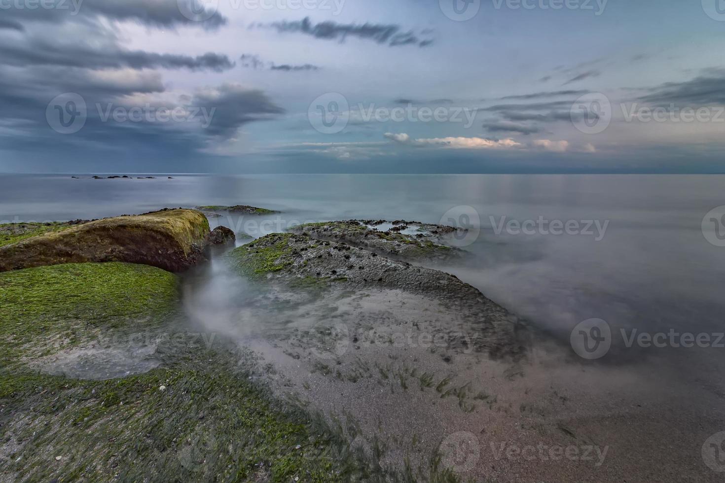 skönhet lugna hav med stenar med alger foto