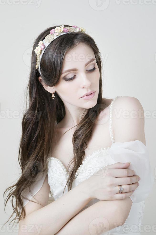ung vacker brud i en vit klänning foto